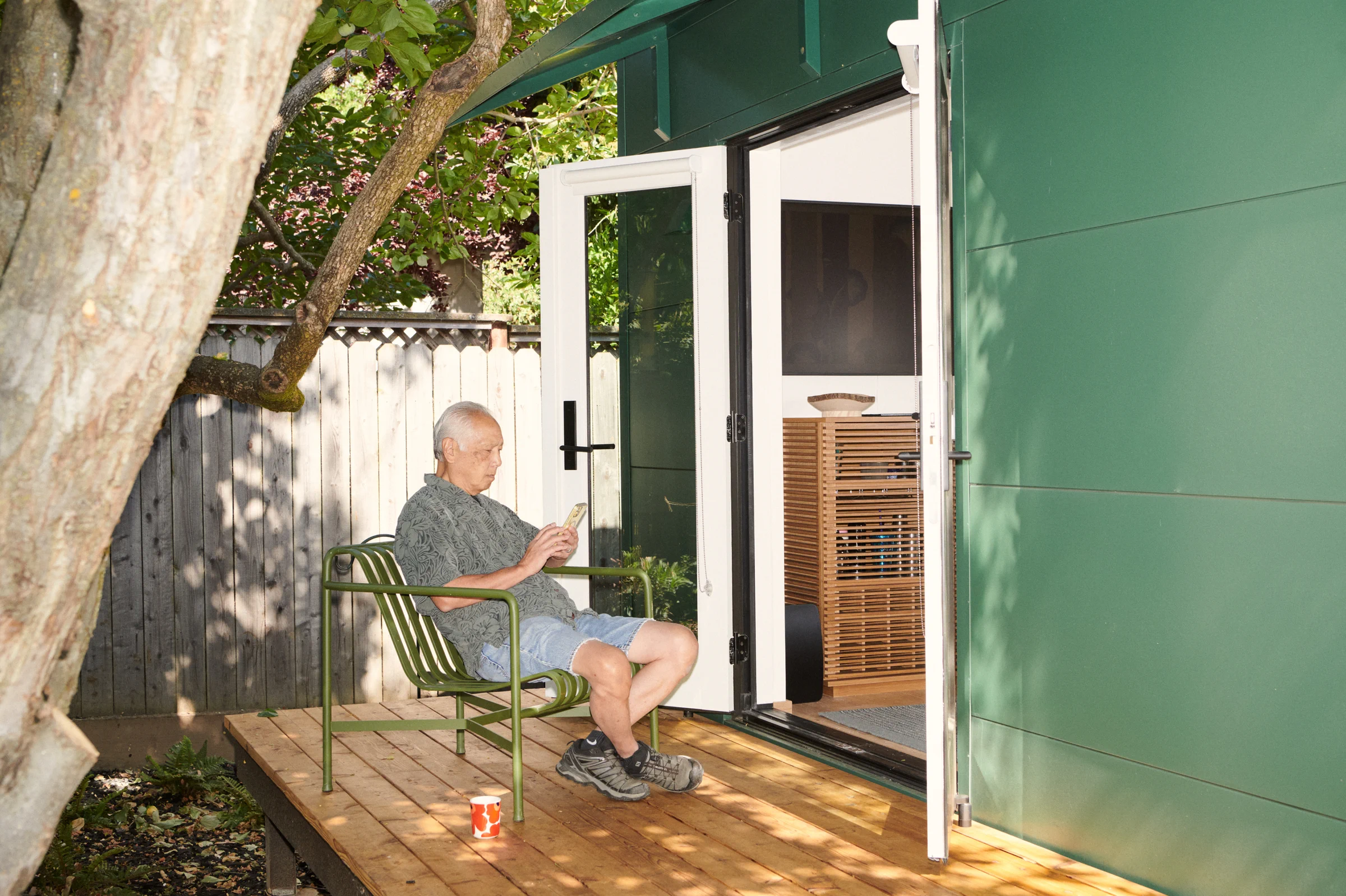 Robert Kuroda relaxing outside his Backyard ADU in evergreen smooth-coated steel.